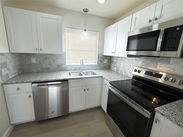 kitchen featuring appliances with stainless steel finishes, decorative light fixtures, sink, and white cabinets