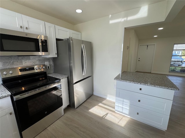 kitchen featuring white cabinetry, light stone counters, light wood-type flooring, and appliances with stainless steel finishes