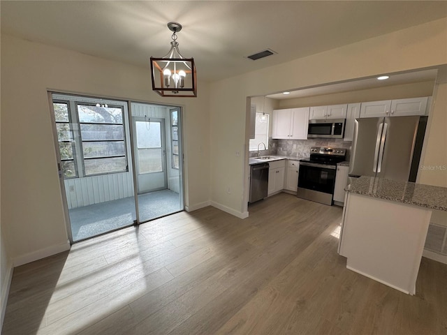 kitchen with white cabinetry, sink, hanging light fixtures, stainless steel appliances, and light wood-type flooring