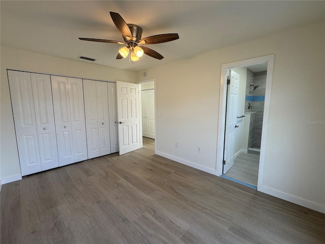 unfurnished bedroom with hardwood / wood-style flooring, connected bathroom, ceiling fan, and a closet