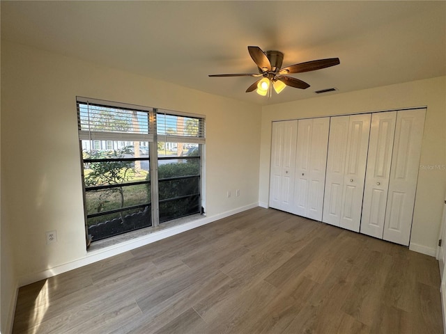 unfurnished bedroom featuring ceiling fan, hardwood / wood-style floors, and a closet