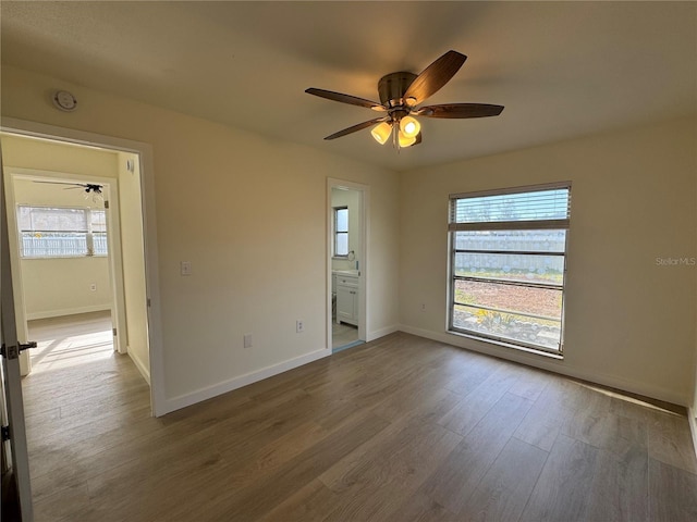 unfurnished bedroom with wood-type flooring, ceiling fan, and ensuite bath