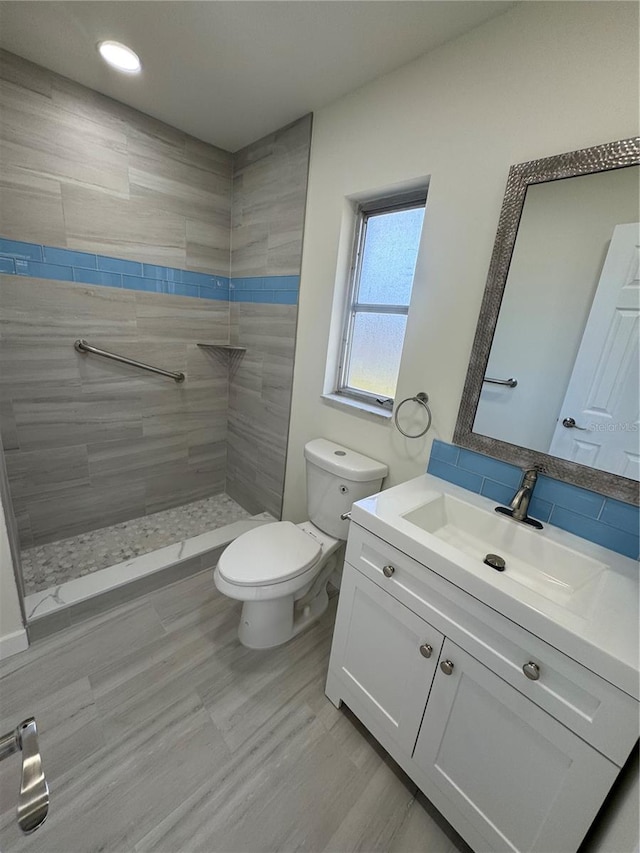 bathroom featuring tiled shower, vanity, and toilet