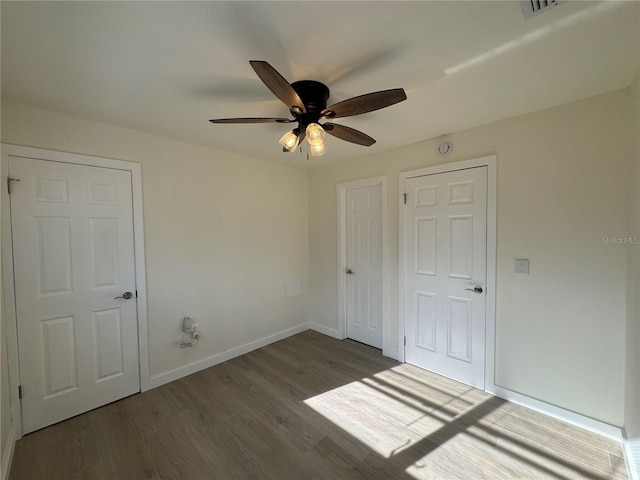 unfurnished bedroom featuring ceiling fan and dark hardwood / wood-style flooring