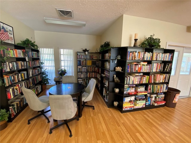 home office with a textured ceiling, light hardwood / wood-style flooring, and a wealth of natural light