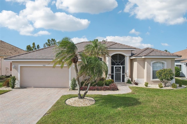 view of front of home with decorative driveway, stucco siding, a front yard, a garage, and a tiled roof