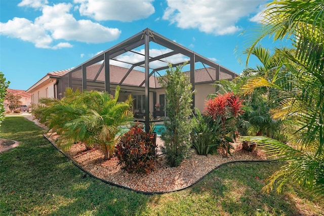 rear view of house featuring a garage, glass enclosure, and a yard