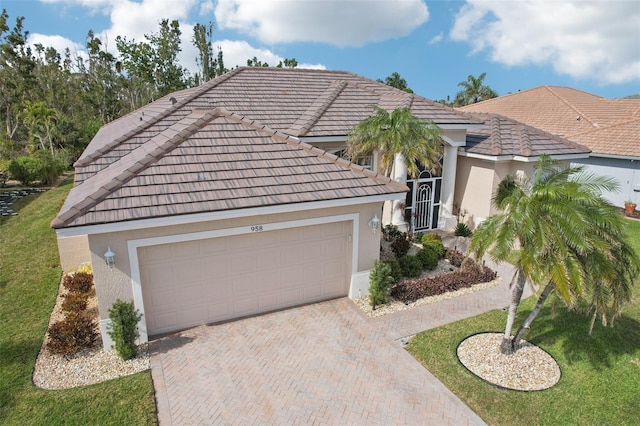 view of front of home featuring an attached garage, a tile roof, decorative driveway, and stucco siding