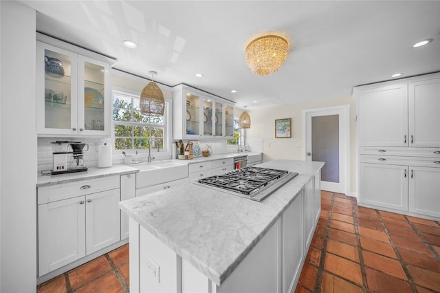 kitchen with stainless steel gas stovetop, sink, and white cabinets