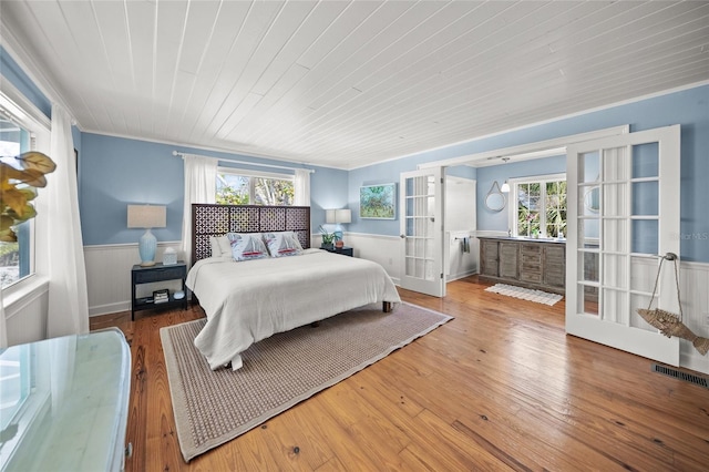 bedroom with multiple windows, hardwood / wood-style floors, wood ceiling, and french doors