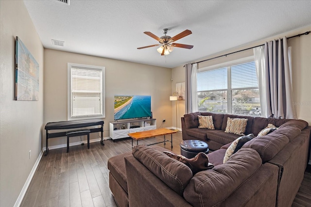 living room with dark hardwood / wood-style flooring, ceiling fan, and a textured ceiling