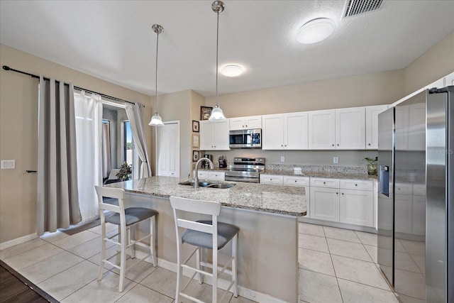 kitchen with white cabinetry, sink, stainless steel appliances, and hanging light fixtures