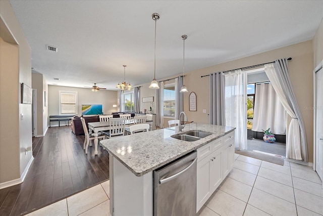 kitchen with sink, hanging light fixtures, a center island with sink, stainless steel dishwasher, and white cabinets