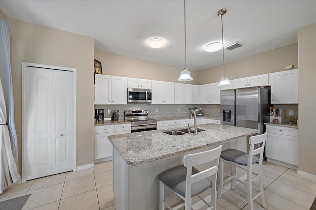 kitchen with sink, a breakfast bar area, white cabinetry, a center island with sink, and stainless steel appliances