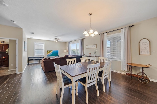 dining space with ceiling fan with notable chandelier and dark hardwood / wood-style flooring