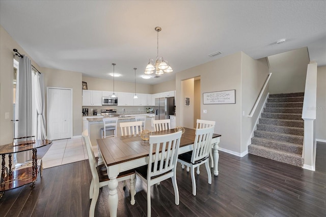 dining area with sink, a chandelier, and dark hardwood / wood-style floors