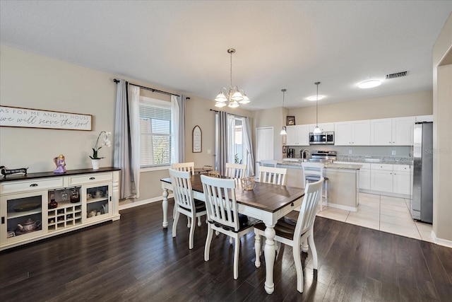 dining room with a notable chandelier, sink, and light wood-type flooring