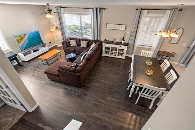 living room featuring dark wood-type flooring and ceiling fan with notable chandelier