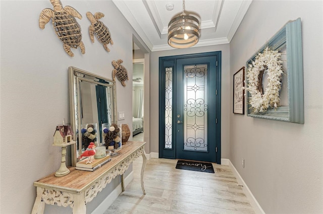 foyer entrance featuring ornamental molding, a raised ceiling, and light hardwood / wood-style floors