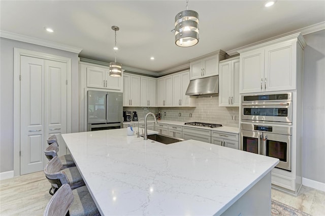 kitchen featuring sink, light stone counters, appliances with stainless steel finishes, pendant lighting, and decorative backsplash