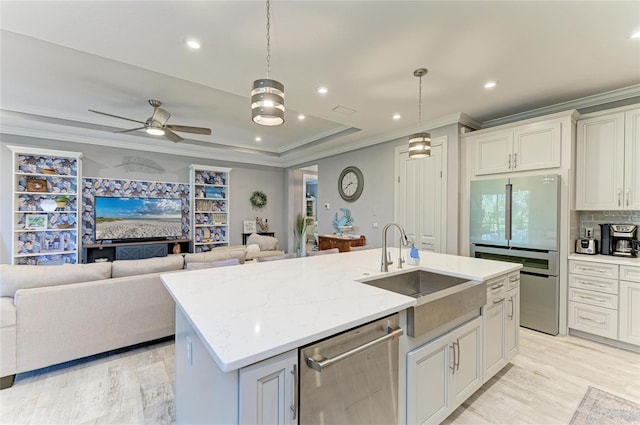 kitchen with a center island with sink, sink, stainless steel dishwasher, and decorative light fixtures