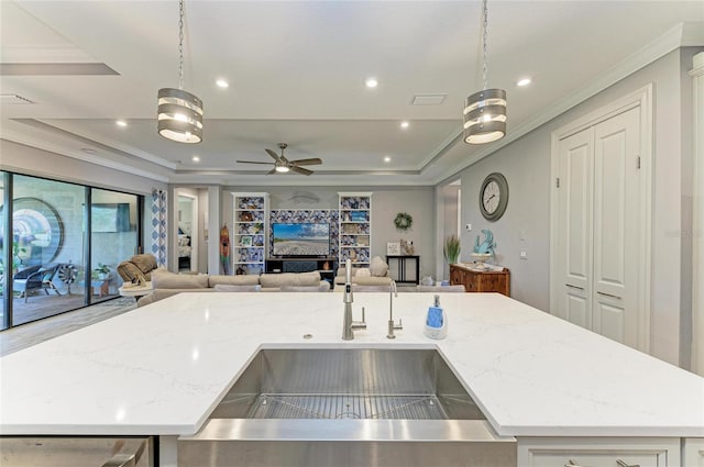 kitchen with pendant lighting, light stone counters, and a center island with sink