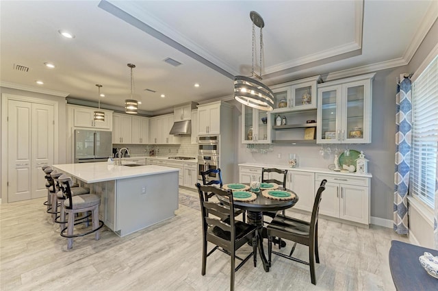 kitchen with sink, tasteful backsplash, an island with sink, pendant lighting, and stainless steel appliances