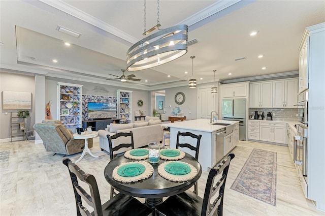 dining space featuring crown molding, a tray ceiling, and light hardwood / wood-style flooring