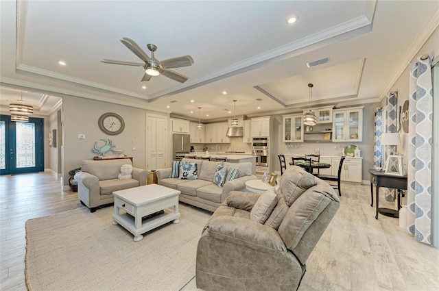 living room featuring crown molding, ceiling fan, light hardwood / wood-style floors, and a tray ceiling