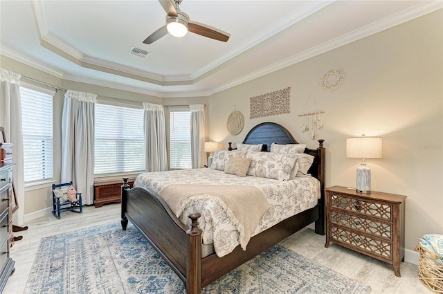 bedroom with crown molding, ceiling fan, light wood-type flooring, and a tray ceiling