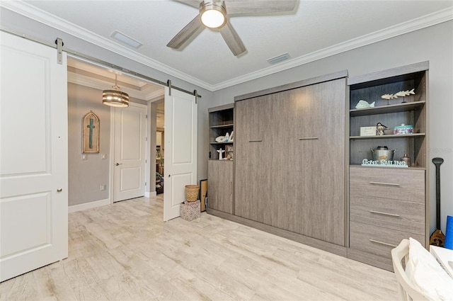 bedroom with ornamental molding, a barn door, ceiling fan, and light wood-type flooring