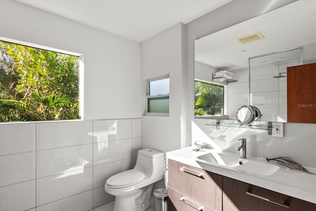 bathroom with vanity, toilet, and tile walls