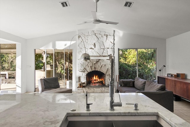 interior space featuring vaulted ceiling, light stone countertops, sink, and a fireplace