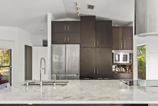 kitchen with ventilation hood, lofted ceiling, sink, stainless steel appliances, and light stone countertops