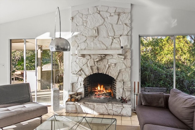 living room featuring light tile patterned flooring, a stone fireplace, and vaulted ceiling