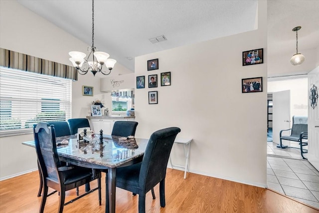 dining room featuring a notable chandelier, lofted ceiling, visible vents, light wood-type flooring, and baseboards