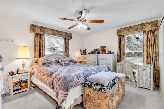 bedroom with light carpet, ceiling fan, and a textured ceiling