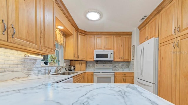 kitchen featuring light stone countertops, sink, white appliances, and decorative backsplash