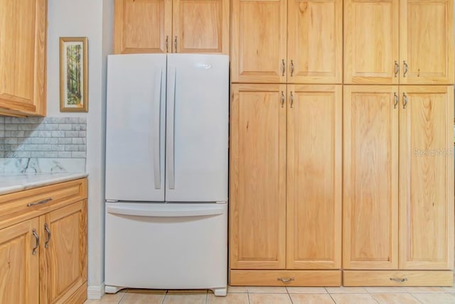 kitchen featuring backsplash, light tile patterned flooring, light brown cabinets, and white fridge