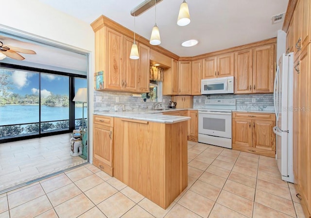 kitchen featuring sink, light tile patterned floors, white appliances, and kitchen peninsula