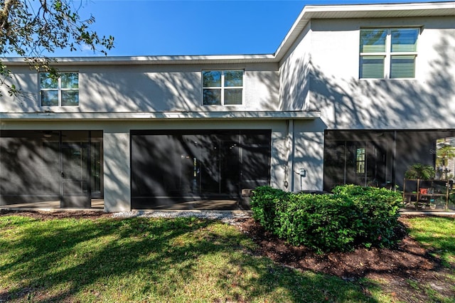 back of property featuring a lawn and a sunroom