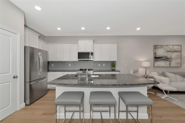 kitchen featuring white cabinetry, light hardwood / wood-style floors, stainless steel appliances, and dark stone counters