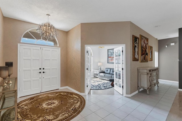 foyer featuring light tile patterned flooring, a chandelier, and a textured ceiling