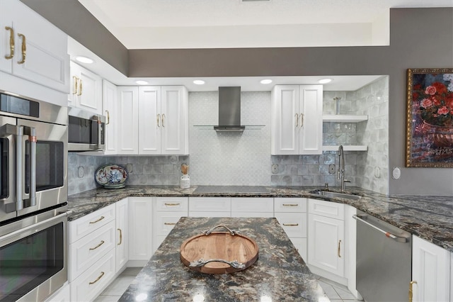 kitchen featuring wall chimney exhaust hood, sink, dark stone countertops, stainless steel appliances, and white cabinets