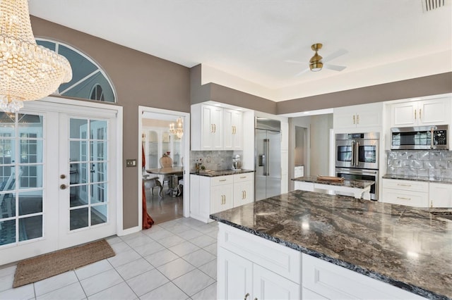 kitchen featuring backsplash, ceiling fan with notable chandelier, white cabinets, and appliances with stainless steel finishes