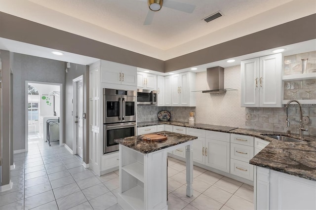 kitchen with appliances with stainless steel finishes, sink, white cabinets, and wall chimney exhaust hood