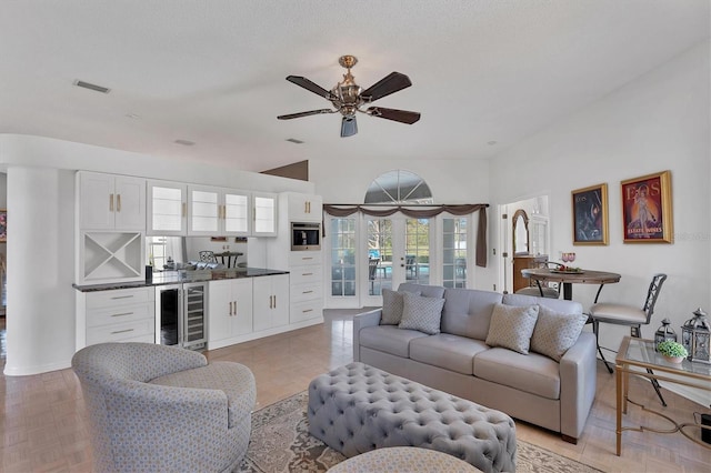 living room with ceiling fan, bar area, french doors, beverage cooler, and light parquet flooring