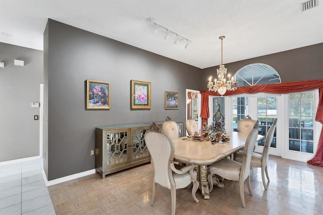 dining room featuring a textured ceiling, light parquet flooring, and a chandelier