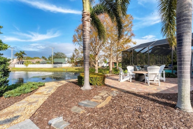 view of yard featuring a patio, a water view, and glass enclosure