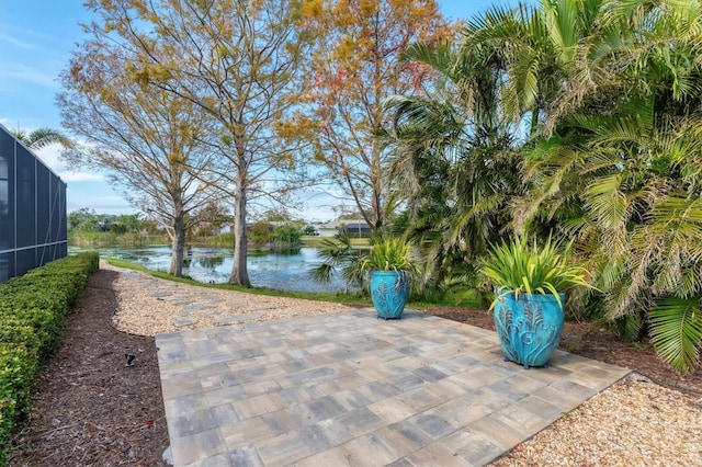 view of patio with glass enclosure and a water view